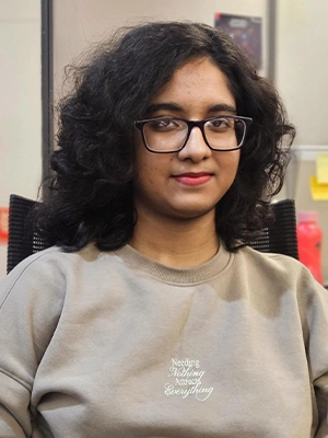 Sonajhoori Maitra, Associate Software Engineer at Vehere, seated in an office environment wearing a light beige sweatshirt.